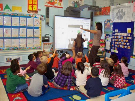 Classroom with teacher and students utilizing a Smartboard for lessons.